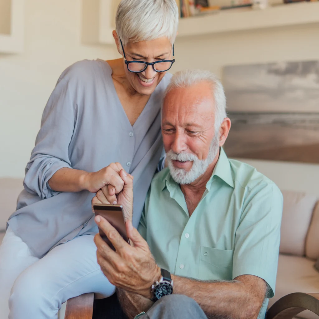 Elderly man and woman looking at a smartphone indoors